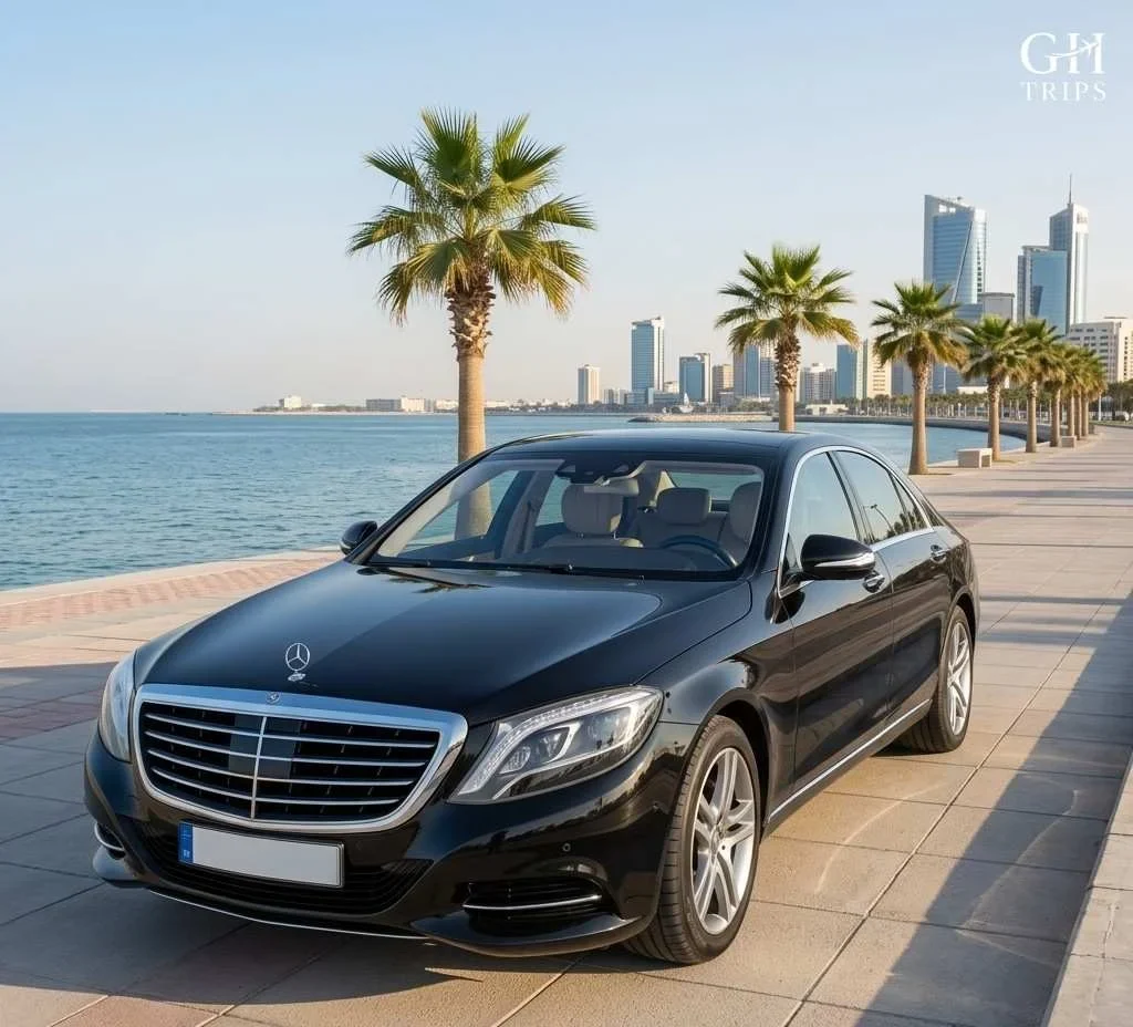 A high-resolution, square photograph of a polished black Mercedes-Benz S-Class luxury chauffeur vehicle parked on the scenic Al Khobar Corniche walkway, Saudi Arabia, with the Arabian Gulf and city skyline in the background - ghtrips.com
