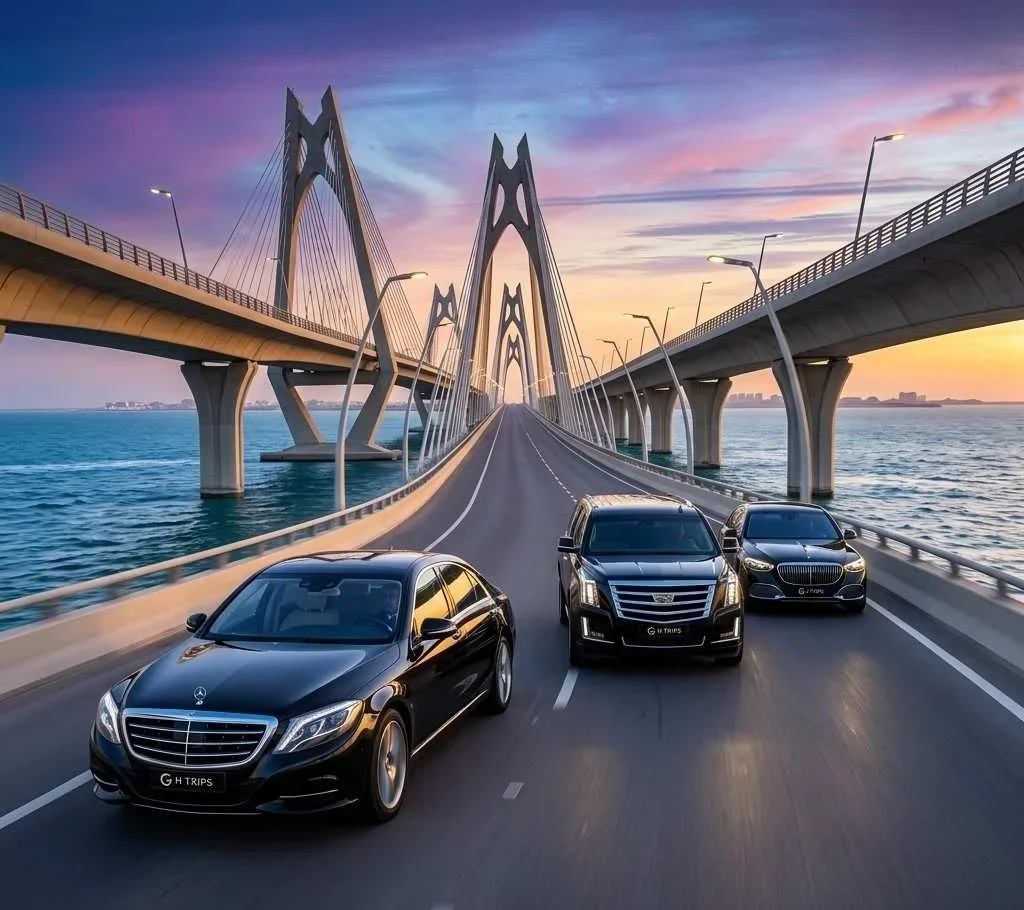 A high-resolution, square photograph capturing a powerful fleet of three glistening black ghtrips.com chauffeur SUVs, including a Cadillac Escalade and GMC Yukon Denali, moving in loose formation across the intricate modern bridge structure of the King Fahd Causeway towards Bahrain, under a dramatic golden-hour sky - ghtrips.com